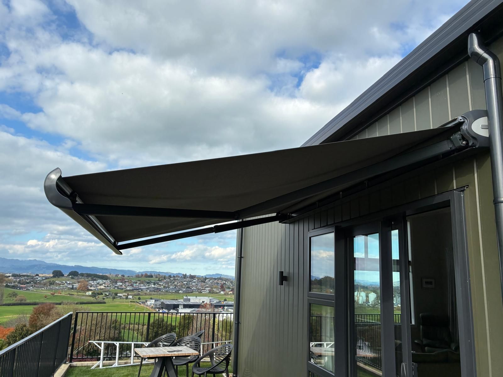 Black folding arm awning extended over a balcony