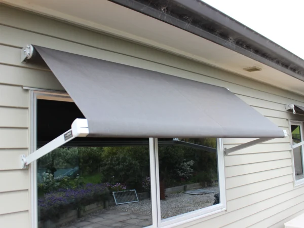 Grey Vertigo drop arm window awning on a home
